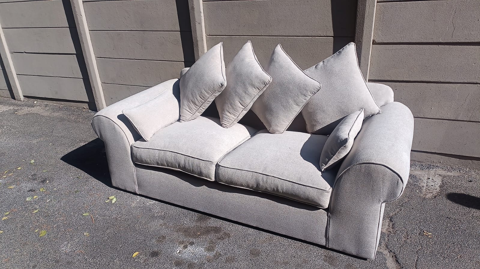 Grey fabric two-seater couch with scatter cushions